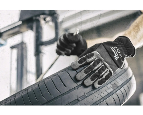 Osoba v pracovních rukavicích drží pneumatiku.