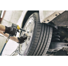 Mechanik mění kolo pomocí rázového utahováku.