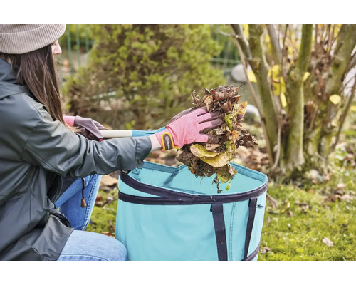 Žena vysypává listí do zahradního textilního pytle.