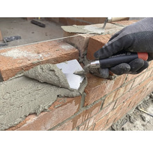 Zedník pokládá cihlu s lžící na staveništi