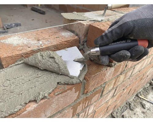 Zedník pokládá cihlu s lžící na staveništi