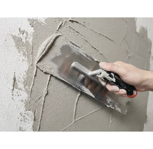 Zedník omítá zeď hladítkem