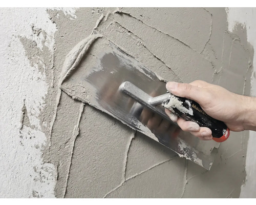 Zedník omítá zeď hladítkem