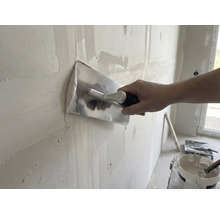 Řemeslník vyhlazuje stěnu pomocí hladítka a omítky