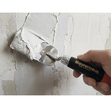 Řemeslník s hladítkem nanáší omítku na zeď. Logo Maurerlob.