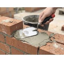 Zednické práce: Cihla je spárována maltou a zednickou lžící.