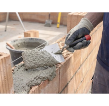 Zedník nanáší maltu a cihly pro stavbu zdi