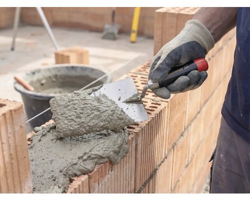 Zedník nanáší maltu a cihly pro stavbu zdi