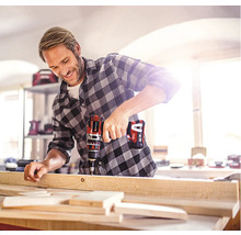 Muž vrtá dřevěnou desku pomocí akumulátorového vrtacího šroubováku.