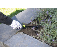 Osoba používá zahradní kultivátor k prokypření půdy ve vyvýšeném záhonu.