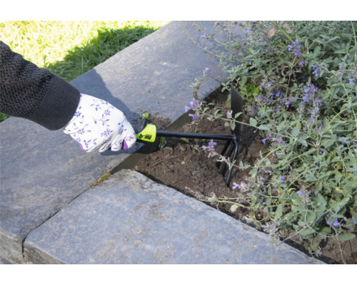 Osoba používá zahradní kultivátor k prokypření půdy ve vyvýšeném záhonu.