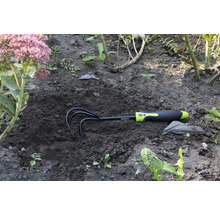 Zahradní hrábě v zemi vedle květiny