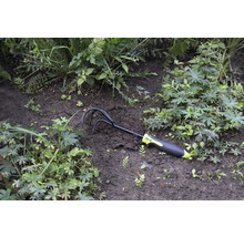 Zahradní kypřič umístěný mezi rostlinami v záhonu