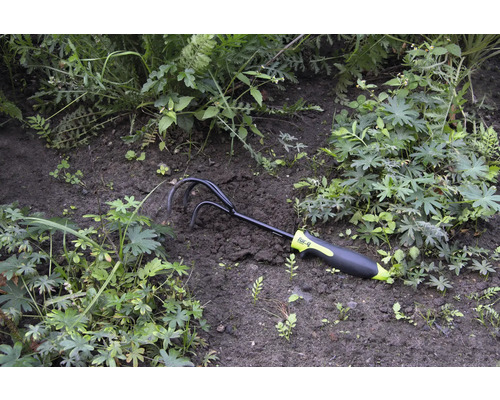 Zahradní kypřič umístěný mezi rostlinami v záhonu