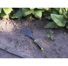 Zahradní hrábě na zahradní půdě s rostlinami