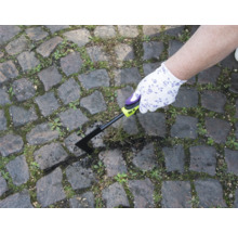 Osoba odstraňuje plevel spárovací škrabkou z dlážděné cesty.