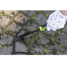 Osoba odstraňuje plevel z mezer mezi dlažebními kostkami pomocí škrabky na spáry for_q.