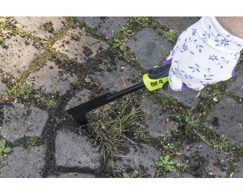 Osoba odstraňuje plevel z mezer mezi dlažebními kostkami pomocí škrabky na spáry for_q.