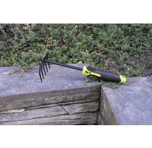 Hrábě na listí a zahradní hrábě s hroty a plastovou rukojetí na kamenné zdi