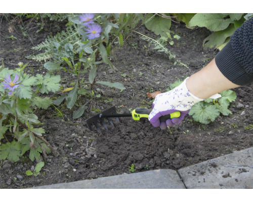 Osoba používá malé hrábě k zahradničení