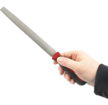 Ruka drží rašpli s plastovou rukojetí