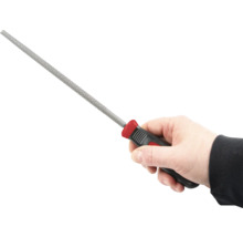 Ruka drží klíčový pilník s plastovou rukojetí.