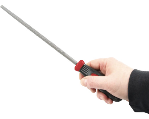 Ruka drží klíčový pilník s plastovou rukojetí.