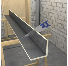 Modrá ruční pila řeže stavební desku ve tvaru L s šedým mřížkovým povrchem na dřevěných kozách ve světlé, nedokončené místnosti.