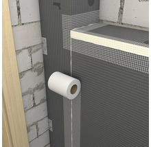 Aplikace bílé mřížkové pásky na spoje šedých stavebních desek na zděné stěně.