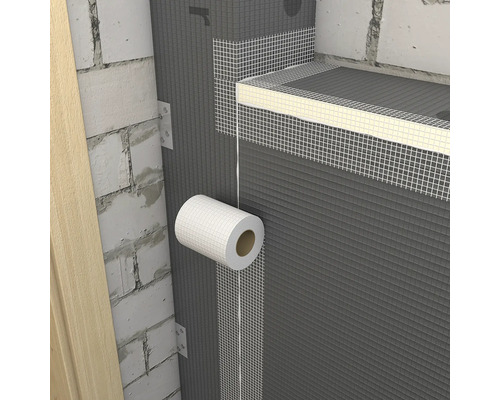 Aplikace bílé mřížkové pásky na spoje šedých stavebních desek na zděné stěně.