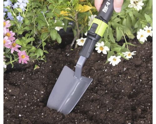 Ruka používá sázecí lopatku for_q ke kopání v hlíně v květinovém záhonu.