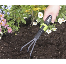 Ruka používá ruční hrabičky for_q v tmavé půdě v záhonu s květinami.