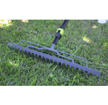 Kovové zahradní hrabě na zeleném trávníku.