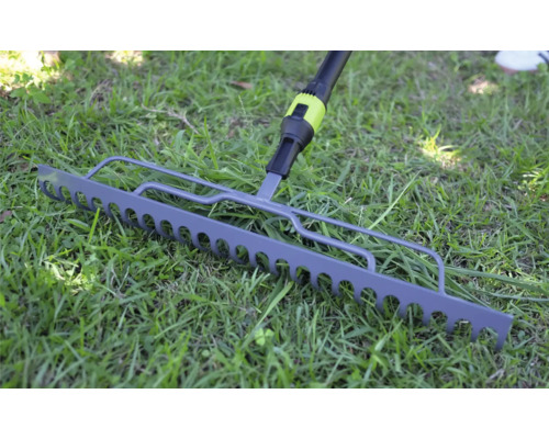 Kovové zahradní hrabě na zeleném trávníku.