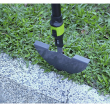 Ořezávač trávníku při práci na okraji trávníku mezi trávou a dlážděnou cestou.