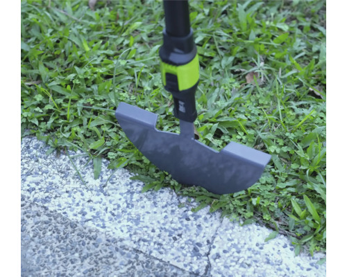 Ořezávač trávníku při práci na okraji trávníku mezi trávou a dlážděnou cestou.