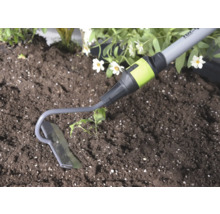 Zahradní motyčka z kovu při práci v půdě vedle rostliny.