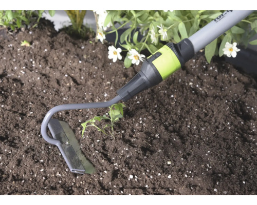 Zahradní motyčka z kovu při práci v půdě vedle rostliny.