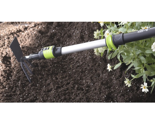 Kombinované zahradní nářadí for_q s teleskopickou násadou v půdě vedle květin.
