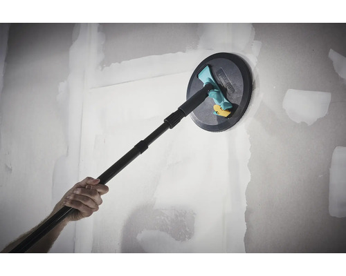 Ruční bruska Wolfcraft s teleskopickou násadou při broušení vytmelené sádrokartonové stěny.