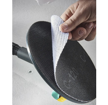 Ruka připevňuje bílý mřížkový brusný kotouč na černý kulatý brusný talíř brusky na sádrokarton.