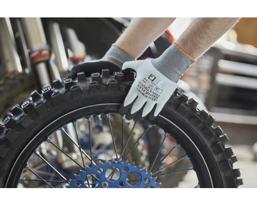 Pracovní rukavice Gebol Master Flex Cool a Touch držící motocyklovou pneumatiku s drapáky v dílně.