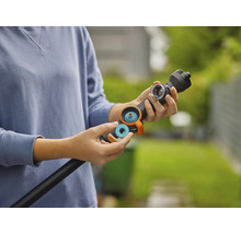 Osoba vkládá modrý těsnicí kroužek nebo filtr do černé zalévací tyče pro zavlažování zahrady.