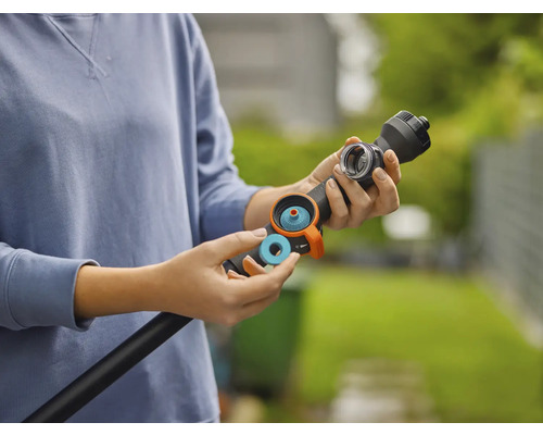 Osoba vkládá modrý těsnicí kroužek nebo filtr do černé zalévací tyče pro zavlažování zahrady.