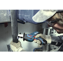 Řemeslník řeže tmavou trubku akumulátorovou pilou ocaskou Bosch Professional v pracovním prostoru se stříbrnými kovovými trubkami.