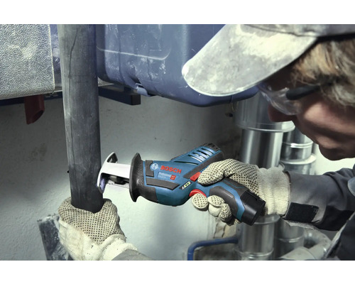 Řemeslník řeže tmavou trubku akumulátorovou pilou ocaskou Bosch Professional v pracovním prostoru se stříbrnými kovovými trubkami.