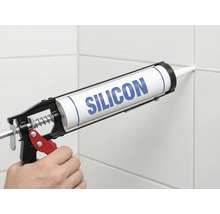 Nanášení silikonu pomocí vytlačovací pistole na spáru obkladů.