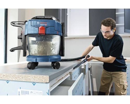 Akumulátorový vysavač na mokré a suché vysávání Bosch při čištění pracovního stolu v jasné dílně.