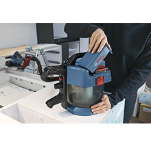 Osoba vkládá 18voltový akumulátor do akumulátorového vysavače Bosch Professional GAS 18 Volt-1 v dílně.