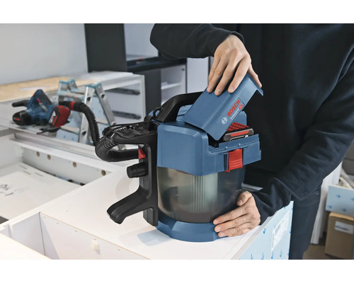 Osoba vkládá 18voltový akumulátor do akumulátorového vysavače Bosch Professional GAS 18 Volt-1 v dílně.